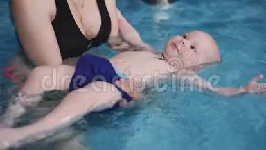妈妈和婴儿在游泳池里游泳。 游泳训练。